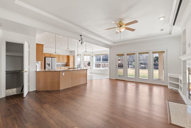 unfurnished living room featuring ceiling fan, recessed lighting, dark wood finished floors, a tiled fireplace, and a raised ceiling