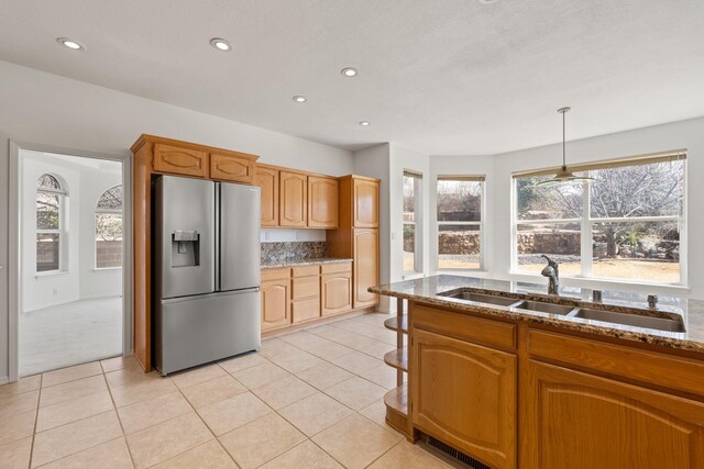 kitchen with tasteful backsplash, stainless steel fridge with ice dispenser, stone counters, a sink, and light tile patterned flooring