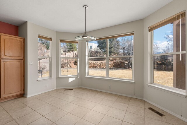 unfurnished dining area featuring a healthy amount of sunlight, visible vents, and baseboards