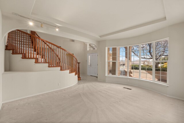 foyer with stairway, visible vents, a tray ceiling, and carpet flooring