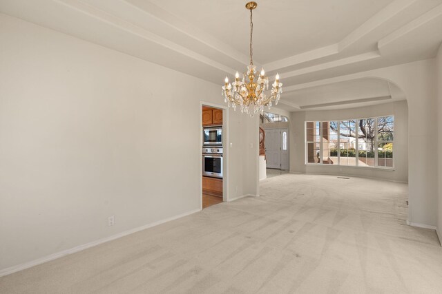 unfurnished dining area featuring a tray ceiling, arched walkways, light colored carpet, a chandelier, and baseboards