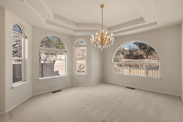 empty room featuring a tray ceiling, carpet, and visible vents