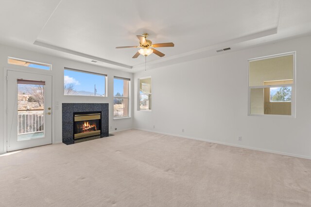 unfurnished living room featuring a fireplace with flush hearth, carpet, a raised ceiling, and visible vents