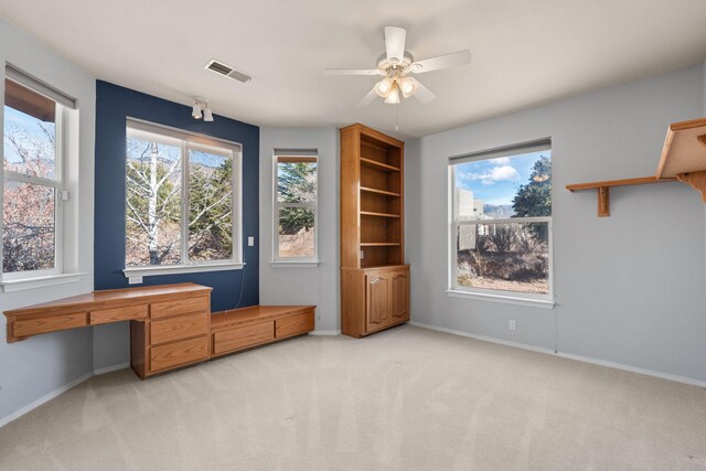 office area featuring light carpet, a wealth of natural light, visible vents, and baseboards