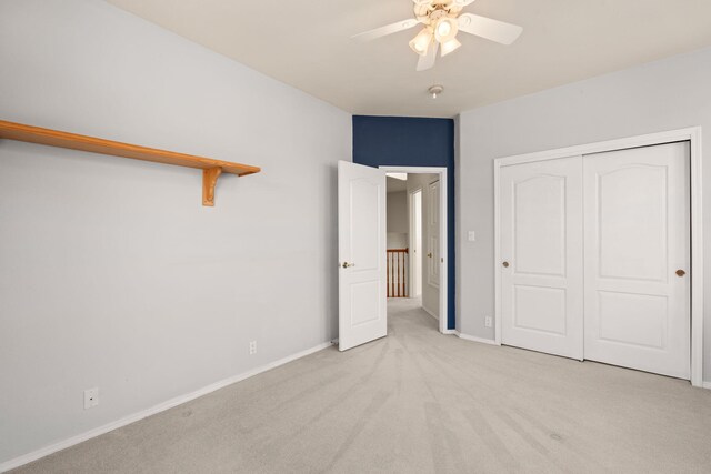 unfurnished bedroom featuring a ceiling fan, a closet, light colored carpet, and baseboards