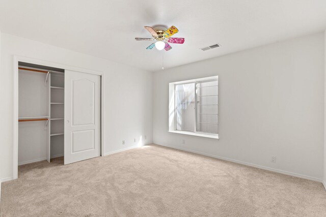 unfurnished bedroom featuring baseboards, visible vents, ceiling fan, carpet floors, and a closet