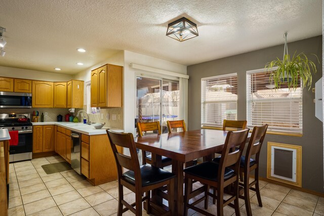 kitchen featuring light tile patterned flooring, sink, a textured ceiling, appliances with stainless steel finishes, and backsplash