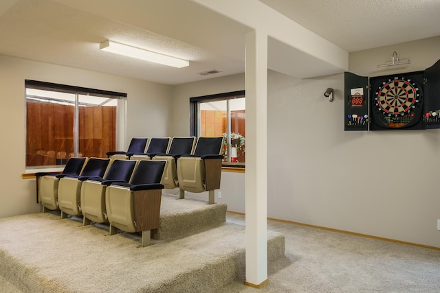 home theater with a wealth of natural light, light colored carpet, and a textured ceiling