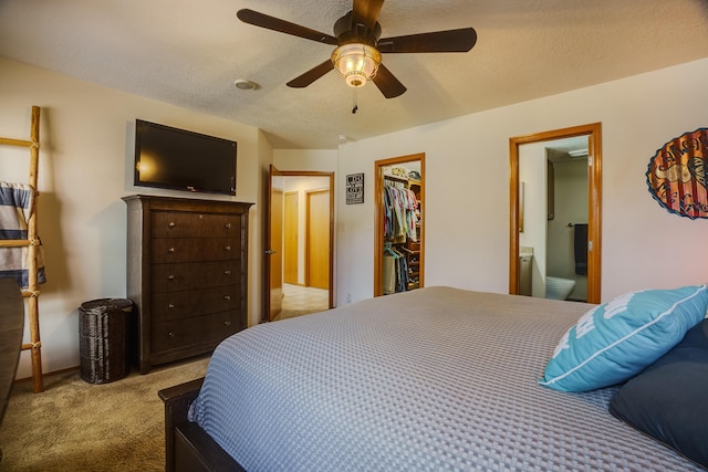 bedroom with ceiling fan, ensuite bath, light carpet, and a textured ceiling