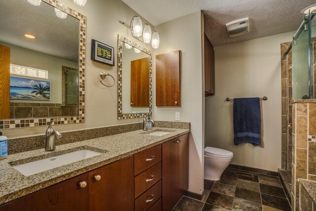 bathroom featuring vanity, a tile shower, a textured ceiling, and toilet