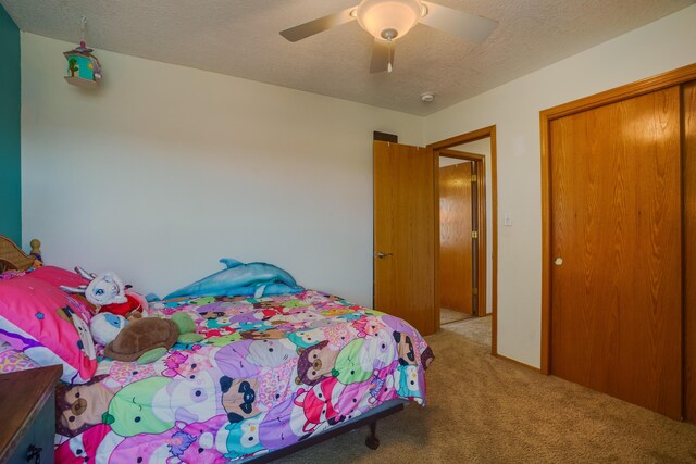 carpeted bedroom featuring ceiling fan, a textured ceiling, and a closet