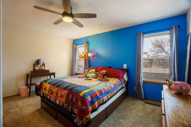 carpeted bedroom featuring ceiling fan and a textured ceiling