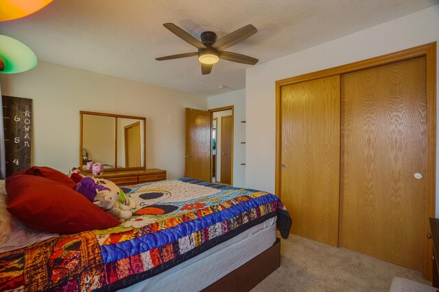 carpeted bedroom featuring ceiling fan, a closet, and a textured ceiling