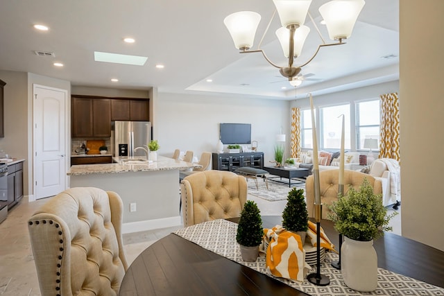 dining space featuring a chandelier, a skylight, and sink