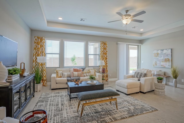 living room with ceiling fan and a tray ceiling