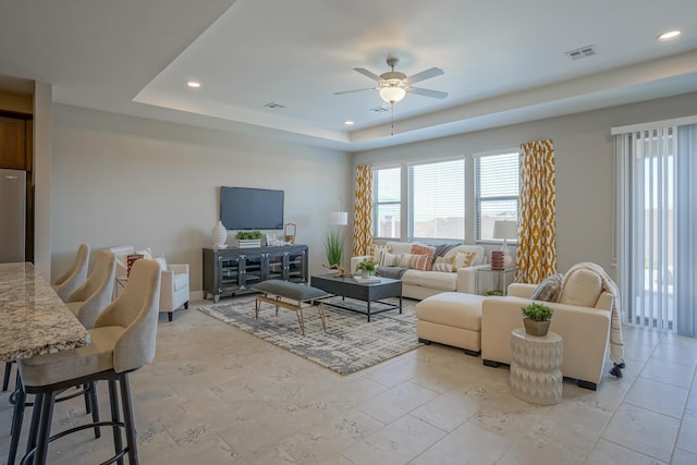 living room featuring a raised ceiling and ceiling fan