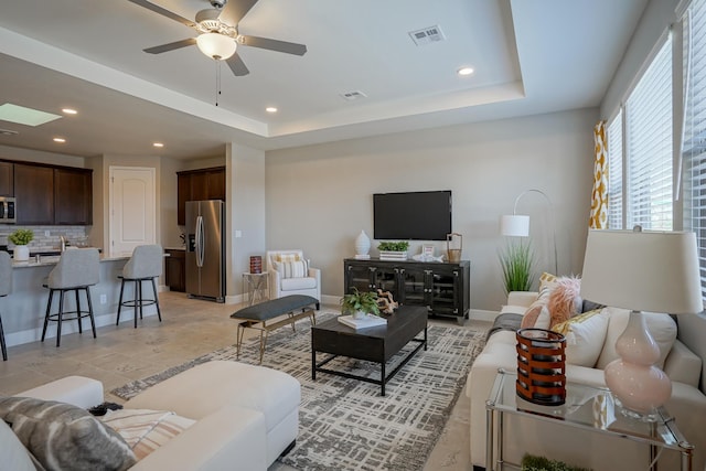 living room featuring ceiling fan and a tray ceiling