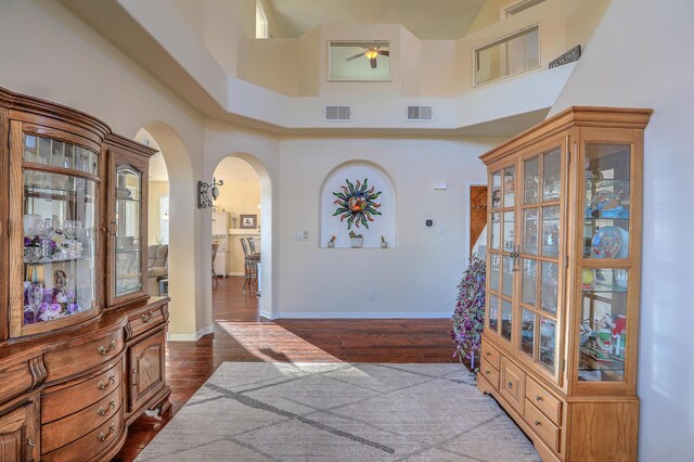 hallway with hardwood / wood-style flooring and a towering ceiling