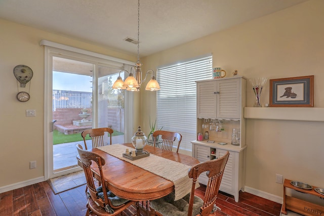 dining space with dark wood-type flooring and a chandelier