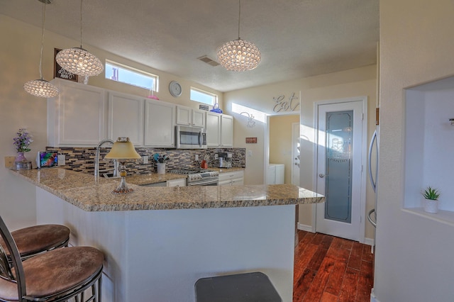 kitchen with pendant lighting, white cabinetry, appliances with stainless steel finishes, and kitchen peninsula