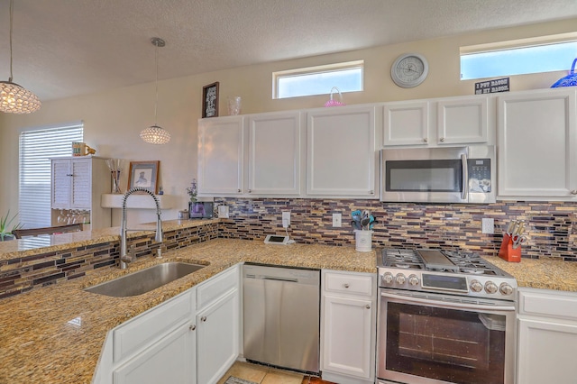 kitchen with pendant lighting, appliances with stainless steel finishes, sink, and white cabinets