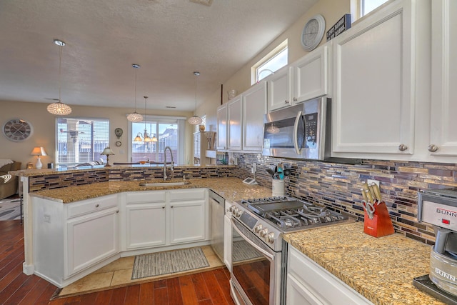 kitchen with white cabinetry, sink, hanging light fixtures, kitchen peninsula, and stainless steel appliances