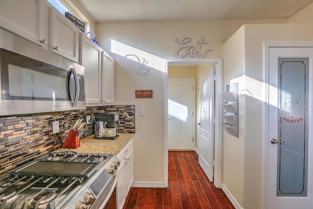 kitchen featuring stainless steel appliances, tasteful backsplash, white cabinetry, and dark hardwood / wood-style flooring