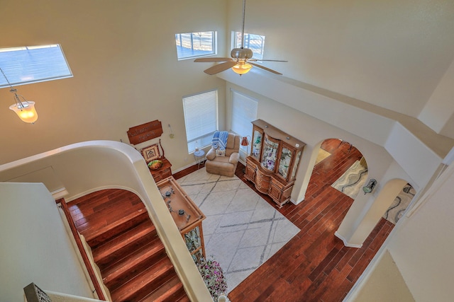 staircase with wood-type flooring, a towering ceiling, and ceiling fan