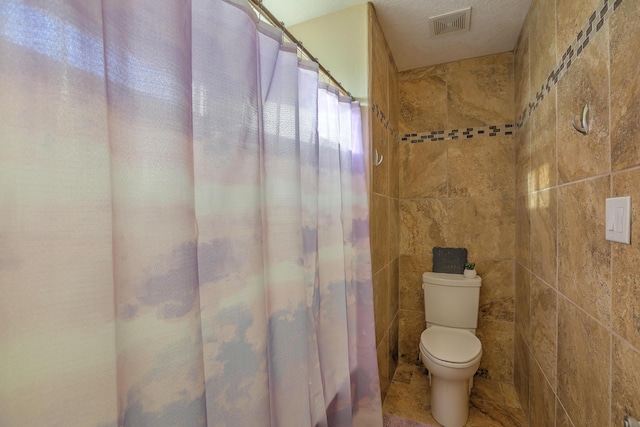 bathroom featuring tile walls, a textured ceiling, and toilet