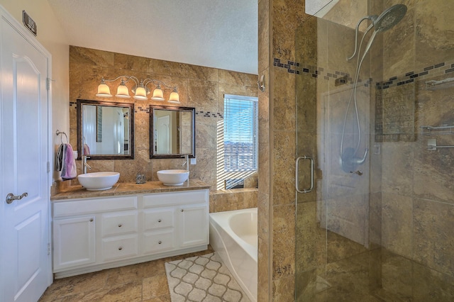 bathroom featuring plus walk in shower, tile walls, vanity, and a textured ceiling