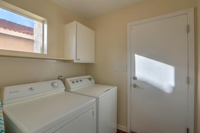 clothes washing area featuring cabinets and washing machine and clothes dryer