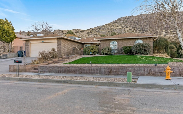 single story home with a garage, concrete driveway, brick siding, and a front lawn