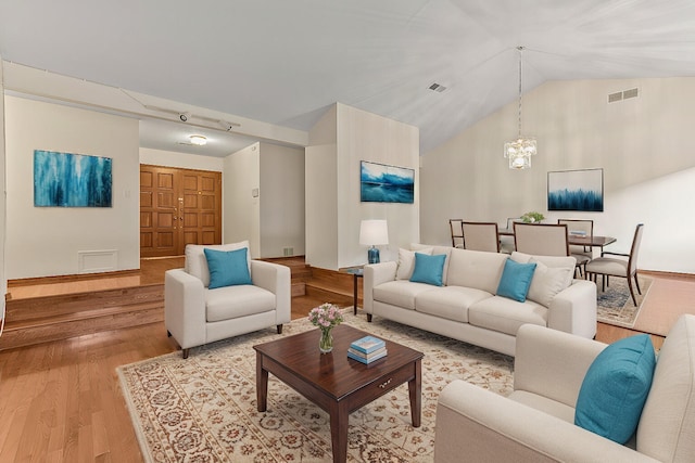 living room featuring an inviting chandelier, high vaulted ceiling, and light wood-type flooring