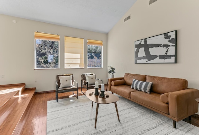 living room featuring hardwood / wood-style flooring, visible vents, and vaulted ceiling