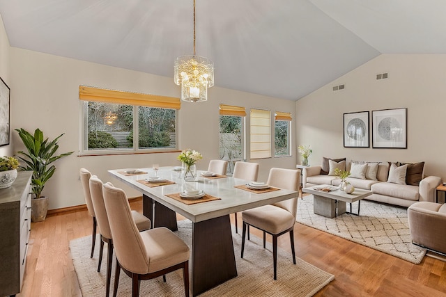 dining room featuring vaulted ceiling, a chandelier, and light wood-type flooring