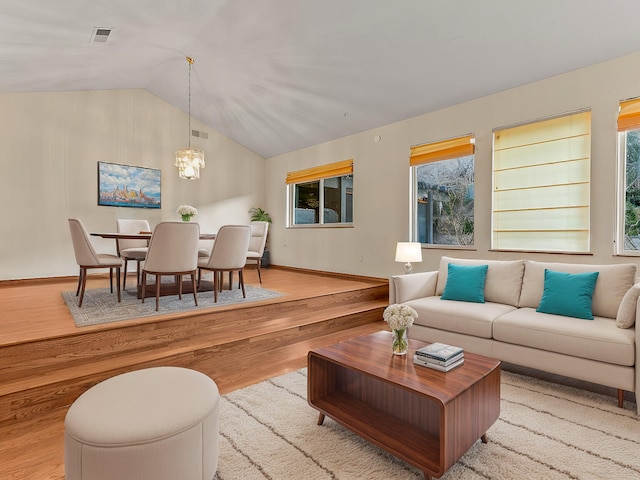 living room with lofted ceiling, light hardwood / wood-style flooring, and an inviting chandelier