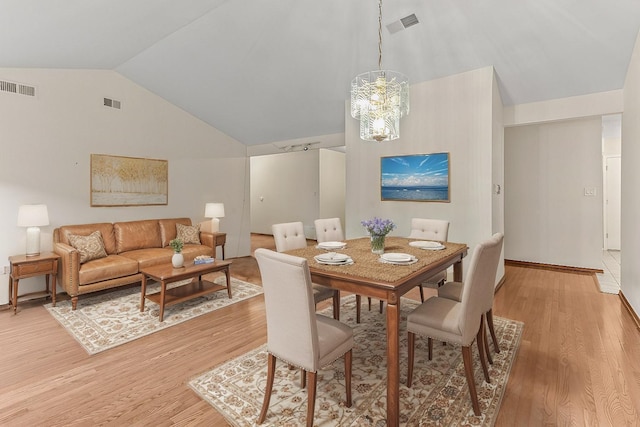 dining space featuring lofted ceiling, a notable chandelier, and light hardwood / wood-style floors