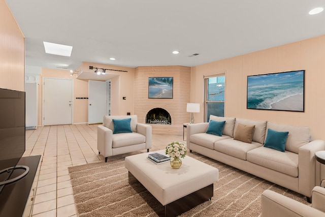 tiled living room featuring a brick fireplace and a skylight