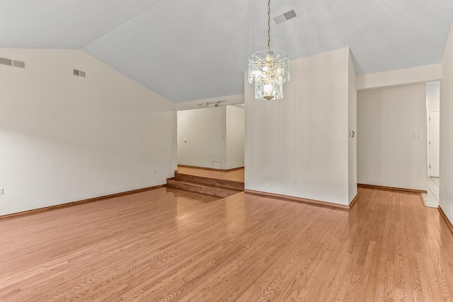 unfurnished dining area with vaulted ceiling, an inviting chandelier, and light wood-type flooring