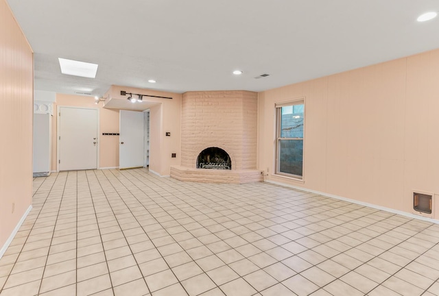 unfurnished living room featuring light tile patterned flooring and a large fireplace