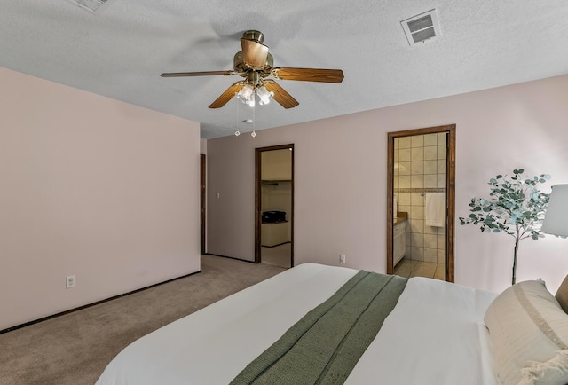 bedroom with light carpet, visible vents, ensuite bath, ceiling fan, and a textured ceiling