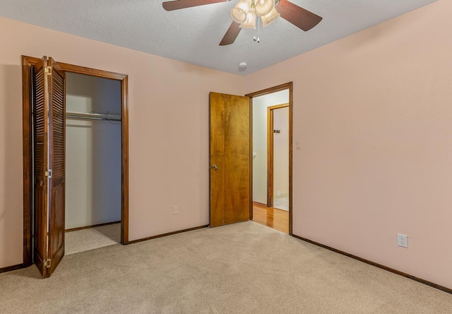 unfurnished bedroom featuring ceiling fan, light colored carpet, a closet, and a textured ceiling