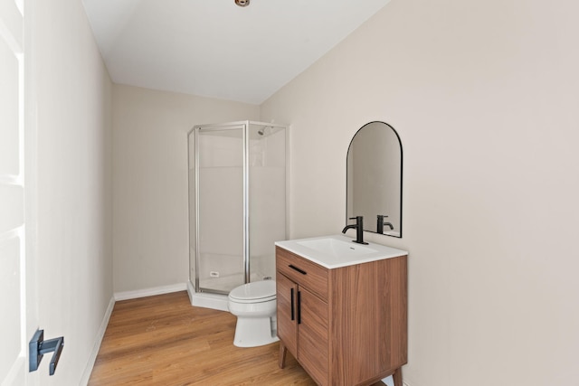 bathroom featuring wood-type flooring, vanity, an enclosed shower, and toilet