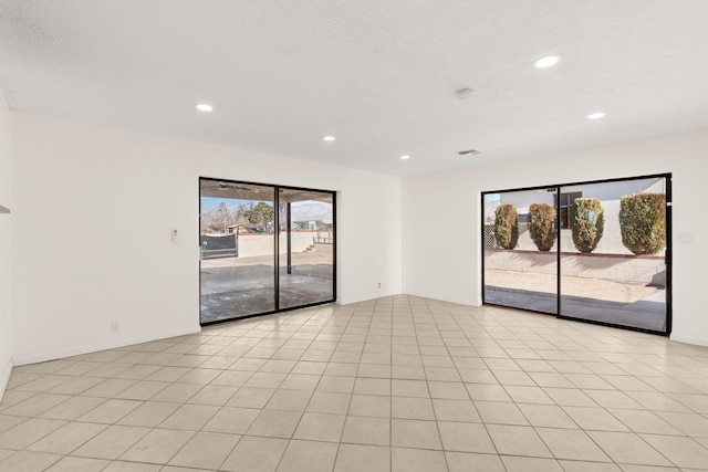 tiled empty room featuring a textured ceiling