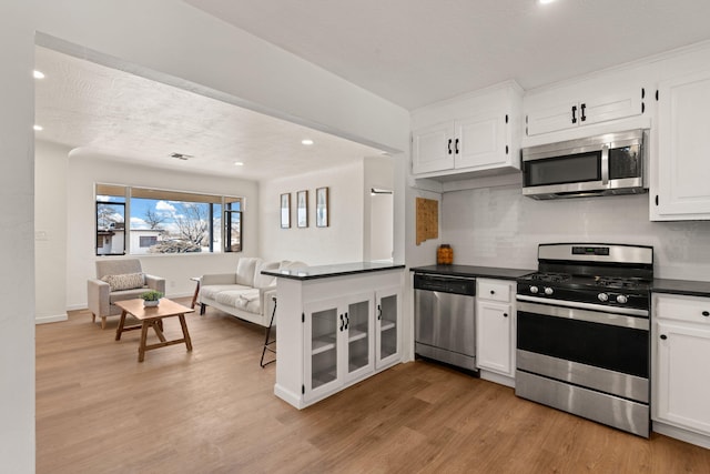 kitchen featuring stainless steel appliances, backsplash, white cabinets, and light wood-type flooring