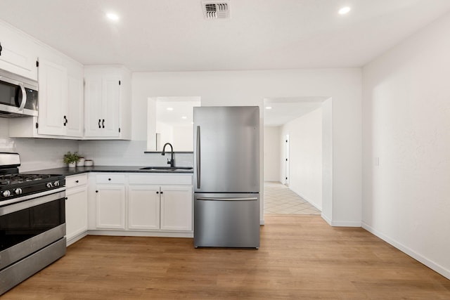 kitchen with light wood-type flooring, appliances with stainless steel finishes, sink, and white cabinets