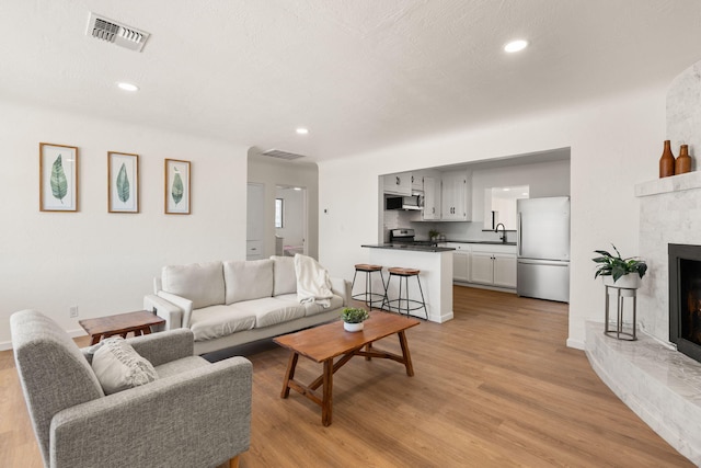 living room with a brick fireplace and light hardwood / wood-style floors