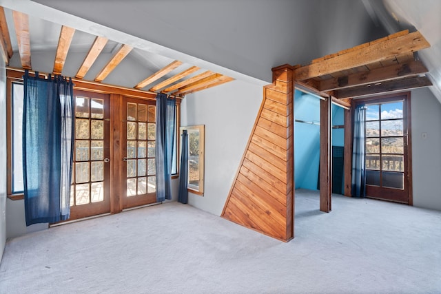 carpeted empty room with lofted ceiling with beams and french doors