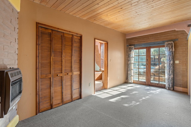 unfurnished bedroom with wood ceiling, heating unit, french doors, light colored carpet, and a closet