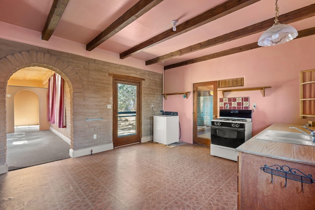 kitchen with washer / dryer, sink, white range with gas stovetop, hanging light fixtures, and beamed ceiling